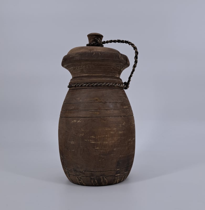 Een kleine, robuuste houten pot met deksel, perfect voor landelijke decoratie.
