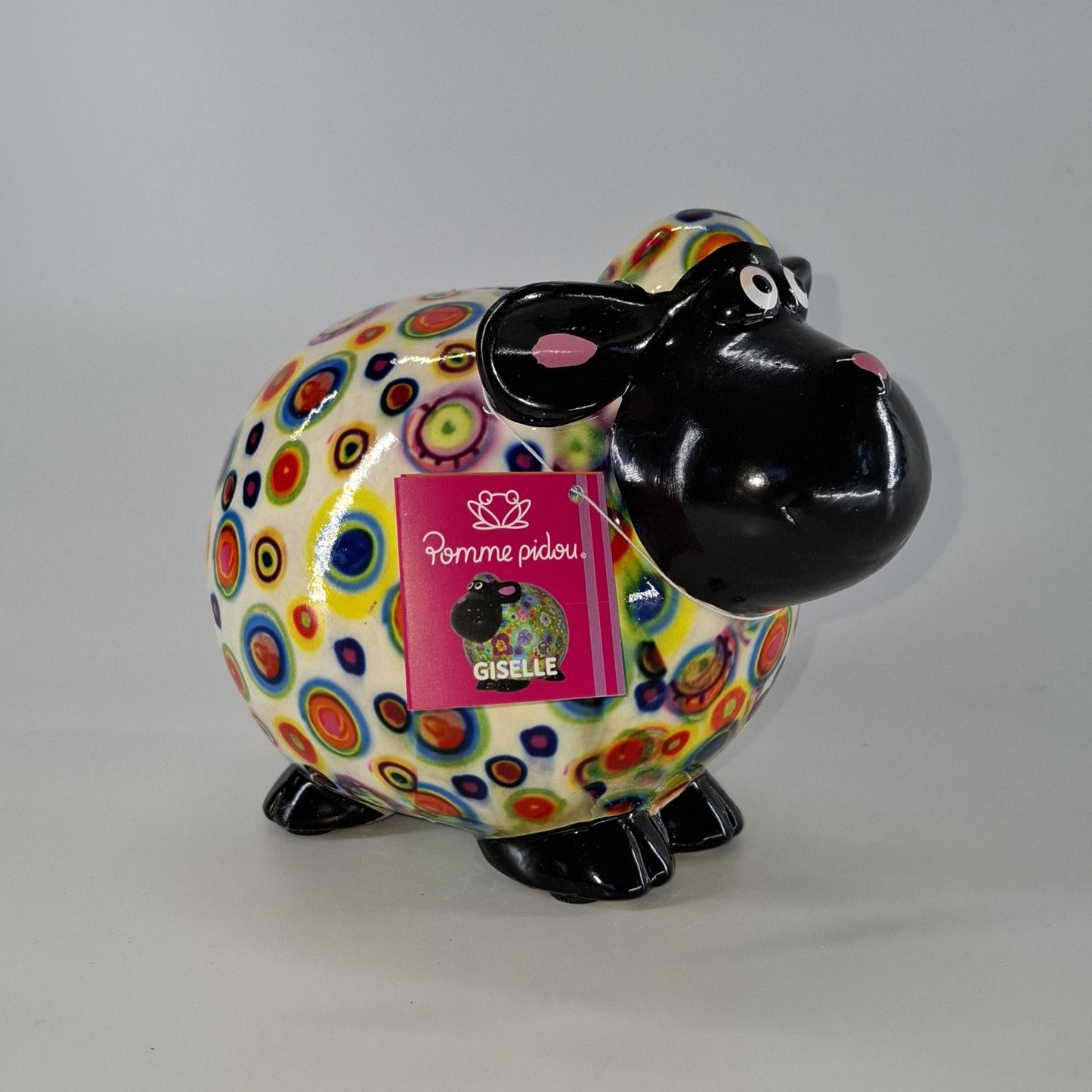 Keramische Pomme Pidou spaarpot in de vorm van een schaap, wit met rondjes. Afmetingen: L17 x B11 x H14 cm. Een speels en origineel cadeau-idee."