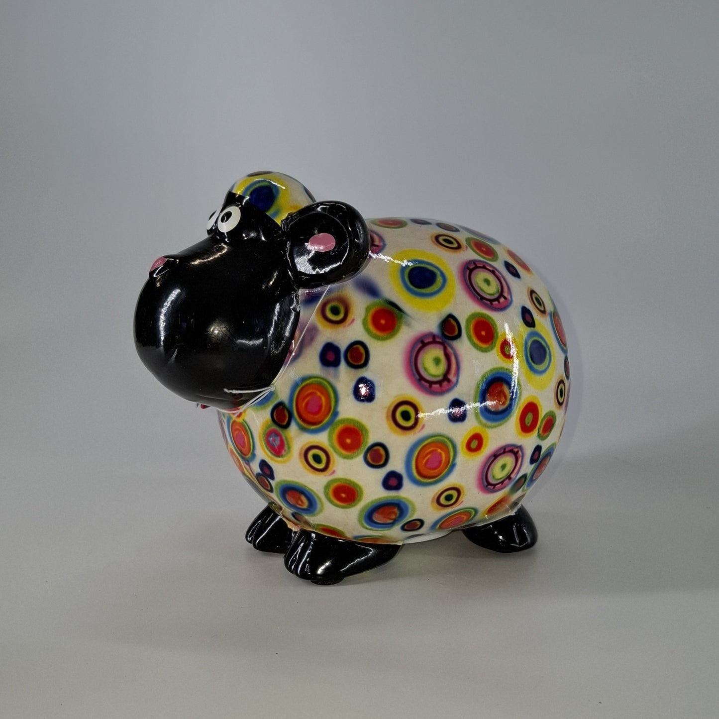 Keramische Pomme Pidou spaarpot in de vorm van een schaap, wit met rondjes. Afmetingen: L17 x B11 x H14 cm. Een speels en origineel cadeau-idee."