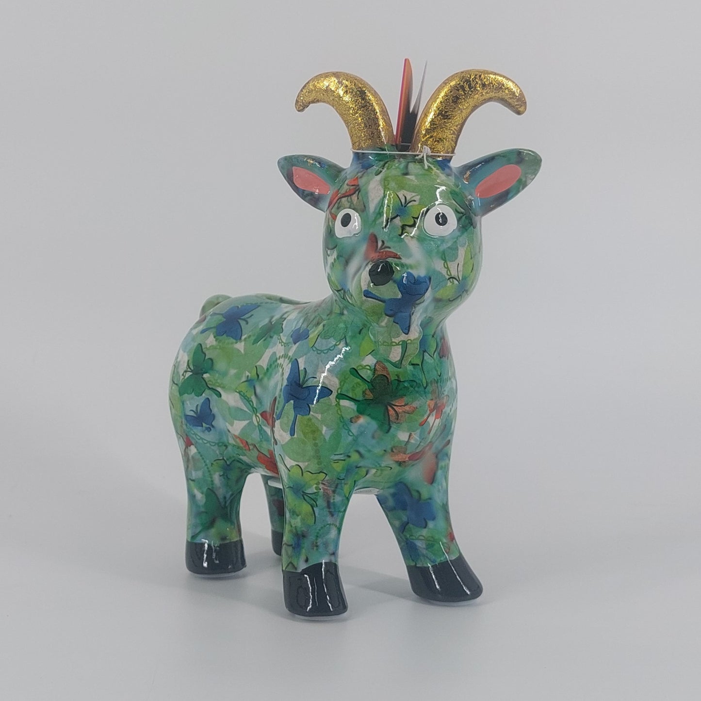 Pomme Pidou spaarpot geit Gabriel in groen met vlinders. Keramische spaarpot met speels design, ideaal als cadeau of decoratie. Afmetingen: L19 x D8.5 x H20cm."