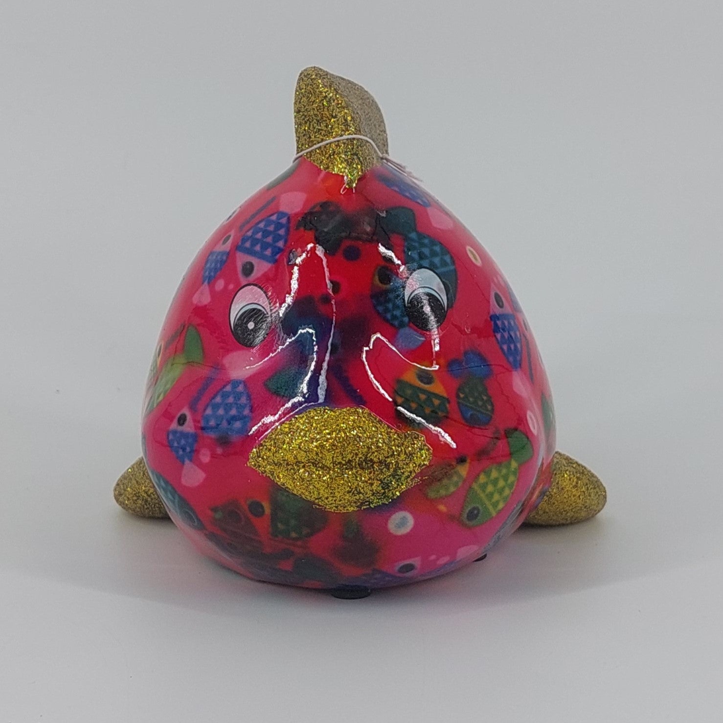 Een kleurrijke keramieken spaarpot in de vorm van een vis, genaamd Calypso. De spaarpot heeft een levendig patroon met visjes en een glanzende afwerking. Perfect als decoratief item en om geld in te sparen.