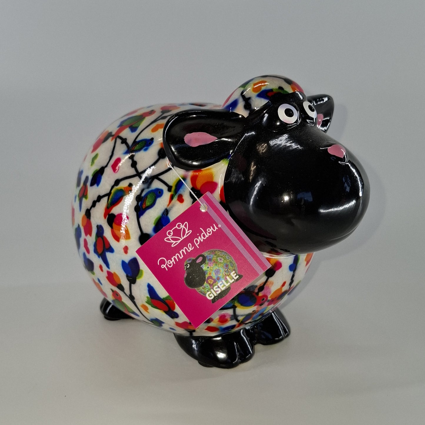 Keramische Pomme Pidou spaarpot in de vorm van een schaap, wit met vogels. Afmetingen: L17 x B11 x H14 cm. Een speels en origineel cadeau-idee."