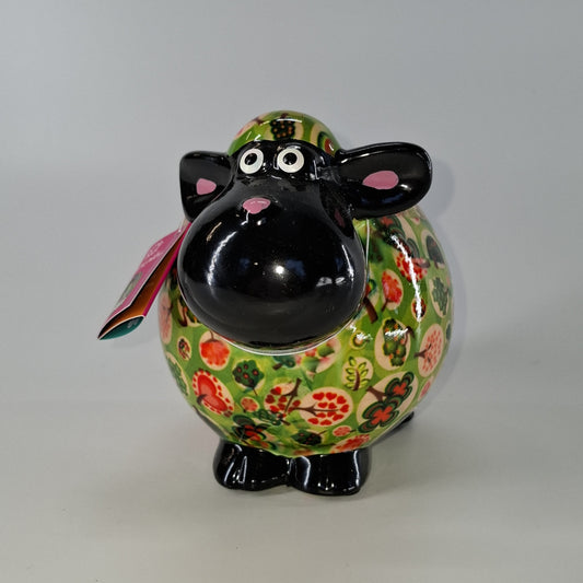 Keramische Pomme Pidou spaarpot in de vorm van een schaap, groen met planten. Afmetingen: L17 x B11 x H14 cm. Een speels en origineel cadeau-idee."